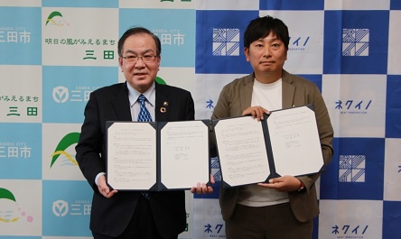 締結式にて署名した調印書を手に記念撮影に応じる、森市長と河田経営本部長の写真