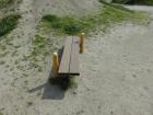 芝生がまだらな場所に置かれた木製の台の上に2本の棒が立っている前屈台の写真
