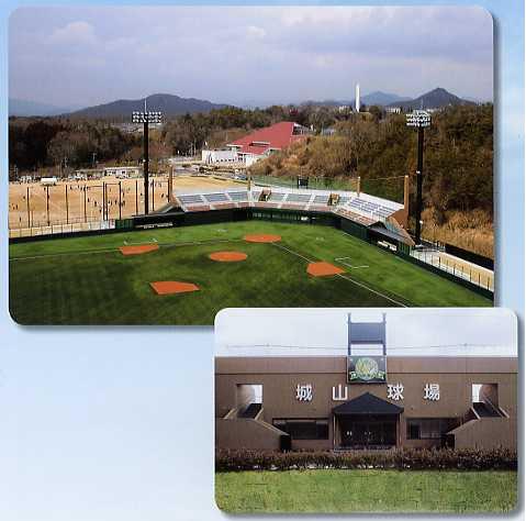緑色の地面が広がる野球場と城山球場と書かれた茶色の建物の写真
