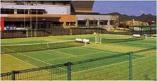 青いフェンス越しの緑色のテニスコートの写真