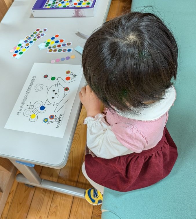 幼児がイラストにシールを貼っている