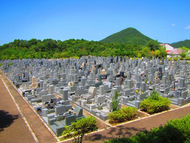 緑の山の手前にお墓がたくさん並んでいる写真