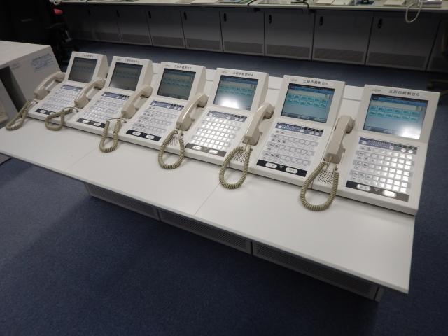 受話器とモニターが付いた、電話機のような機械が横に6つ並んでいる写真
