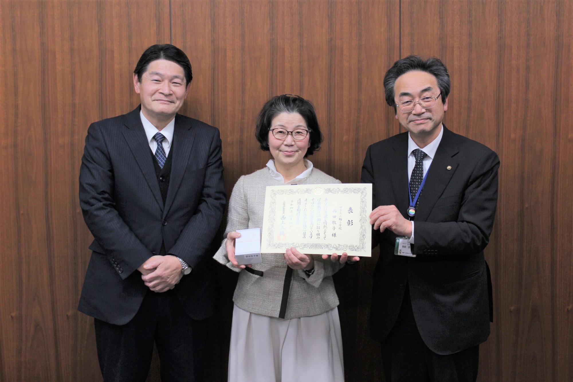 西田牧子教諭が兵庫県優秀教職員表彰の表彰状を笑顔でカメラに向けている写真