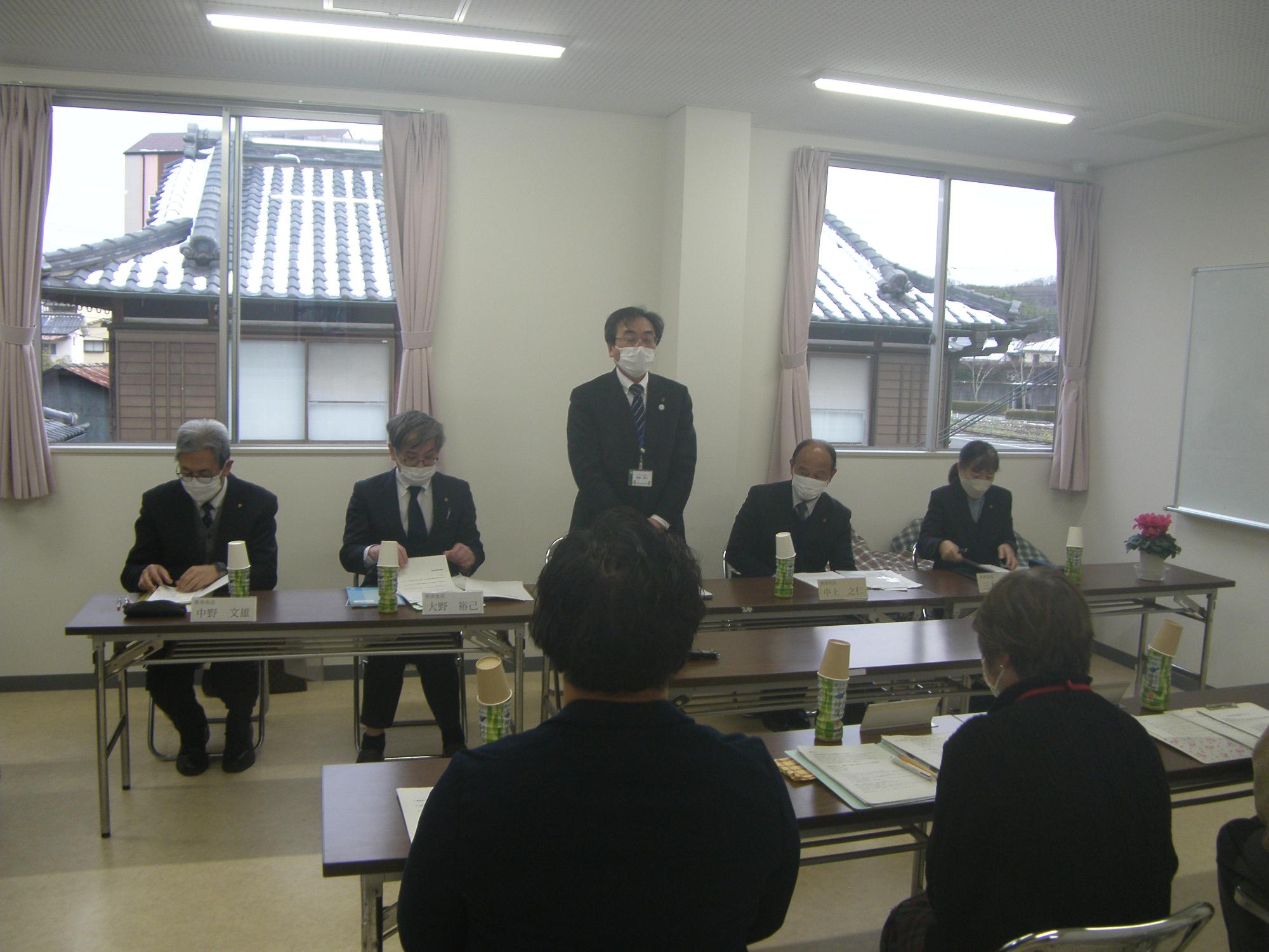 教育懇談会にて起立している発言者と着席して聞いている他の参加者達の写真