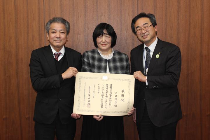 酒井俊子教諭が文部科学大臣優秀教職員表彰の表彰状をカメラに向けている写真
