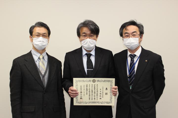 兵庫県優秀教職員の表彰状を持った王子主幹教諭と、西村前校長、鹿嶽教育長の並んでいる写真