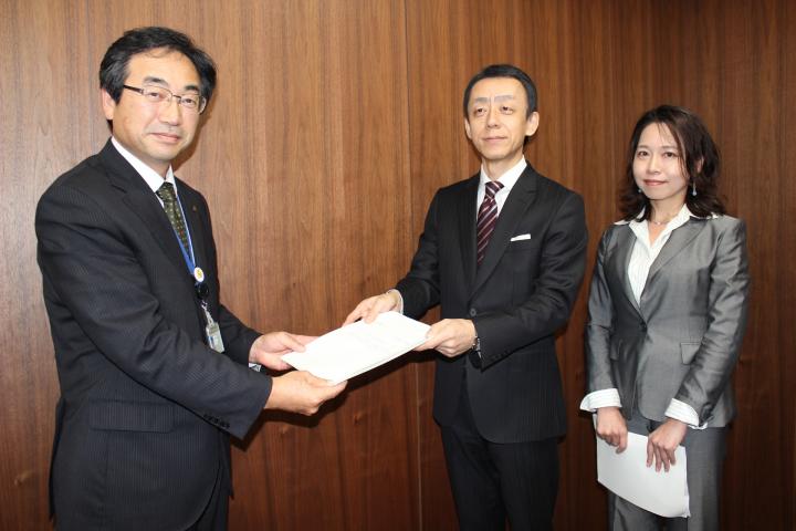 木製の壁を背景に佐藤委員長、中間副委員長から第2期教育振興基本計画の答申を受ける鹿嶽教育長の写真