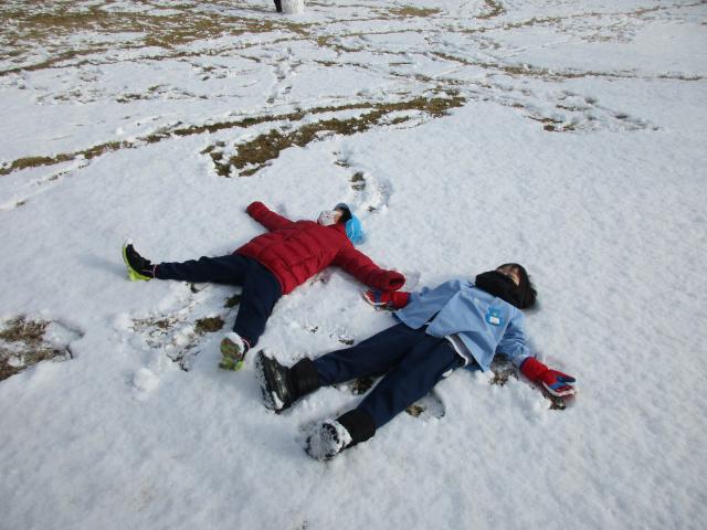 雪の上で大の字に寝て遊ぶ園児達の写真