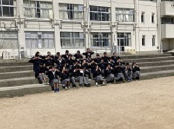 校舎の前の階段に座り両手で顔を覆っている、制服姿の生徒たちの写真
