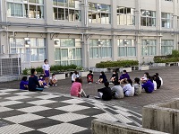 チェック柄の階段が特徴的な広場で円形に生徒たちが座っている様子の写真