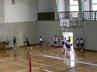 体育館のバスケットゴールの下でバスケットボールの練習をしている生徒たちの写真