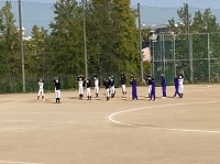 グラウンドの一角で野球のユニフォームを着た生徒たちが円形になって集まっている様子の写真