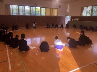 少し広い床張りの部屋に、生徒たちが横に竹刀を置いて円形で正座している様子の写真
