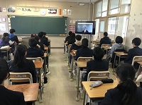 教室に生徒たちが座っていて、右側のモニターを見ている様子の写真