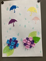 カラフルな傘と折り紙で表現されたあじさいの花が貼り付けられている様子の作品の写真