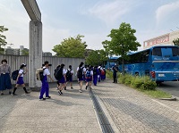 青い観光バスに乗り込むために生徒たちが並んで歩いている様子の写真