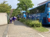 青い観光バスの隣で集合している生徒たちの写真