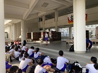 エントランスホールの真ん中に一人の生徒が立ち、それを見上げるように地面に並んで座っている生徒たちの写真