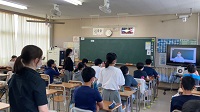 教室に生徒たちが座り、そのうちの一人の生徒が立っている様子の写真