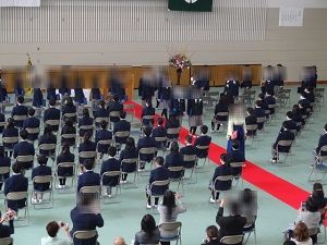 担任の先生を先頭に赤い絨毯の上を歩く卒業生達の写真
