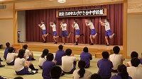 舞台上でジャージ姿の生徒さん達6人が手と足を上げて踊っている様子の写真