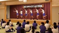 舞台上でジャージ姿の生徒たち6人が大きく体を動かしながら踊っている様子の写真