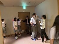 制服姿の生徒たちが廊下で検温をしてもらっている様子の写真