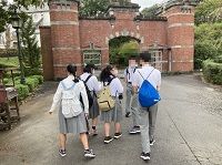 赤いレンガのゲートの前に向かって歩いている生徒たちの写真
