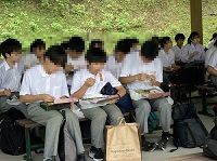 ベンチに座って弁当を食べている男子生徒3人の写真