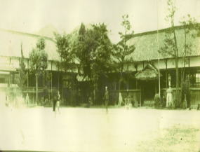 入り口の横に葉が生い茂った木と灯篭がある昭和3年に出来た校舎を写した当時の写真