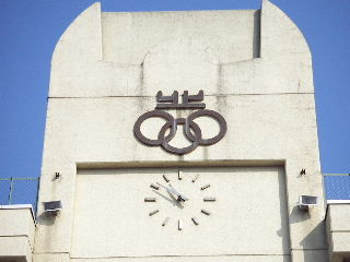 校舎の壁上に取り付けられている志手原小学校の校章と時計を写した写真